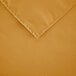 A close-up of a gold rectangular cloth table cover with hemmed edges.