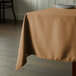 A table with a beige Intedge cloth table cover and a plate on it.
