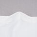 A close up of a white spandex table cover with a folded edge.