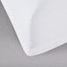A white Snap Drape Contour Table Cover with folded edges on a gray surface.