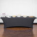 A charcoal Snap Drape spandex table cover on a table with food on it.