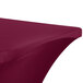 A burgundy Snap Drape Contour Spandex table cover with a curved edge on a table.