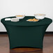 A table set with a hunter green Snap Drape spandex table cover with bowls of food.