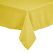 A yellow rectangular polyester table cover with a hem on a table.