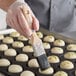 A person using an Ateco boar bristle pastry brush to paint white dough balls.
