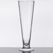 A clear GET Tritan plastic footed pilsner glass on a table.