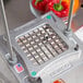 A Nemco Easy Chopper III blade and holder assembly with diced red bell pepper on a metal surface.