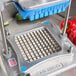 A Nemco Easy Chopper III with a square grid on it over a counter with a bunch of peppers.