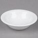 A Tuxton bright white narrow rim china fruit bowl on a white surface.