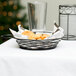 A Tablecraft black metal basket with ramekin holders on a table with food.