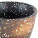 A white stoneware sake cup with black and brown speckles.