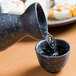 A black ceramic Whittier Nagoya Sake Cup being poured into.
