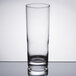 An Arcoroc customizable collins glass with white liquid in it on a table.