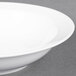 An Arcoroc Daring porcelain bowl with a white rim on a gray surface.