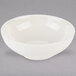 A Tuxton Eggshell China bowl with a small rim on a gray background.
