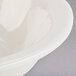 A Tuxton eggshell china grapefruit bowl with a curved edge.