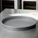 An American Metalcraft hard coat anodized aluminum pizza pan on a floured countertop.