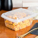 A Genpak clear plastic rectangular lid on a plastic container with food in it.