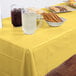 A Mimosa yellow plastic table cover on a table with drinks and snacks.