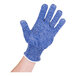 A hand wearing a blue San Jamar cut resistant glove with white trim.