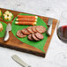 A Tablecraft acacia wood rectangular serving board with cheese and meat on it.