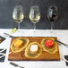 A Tablecraft acacia wood rectangular serving board with wine and cheese on a table.
