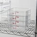 A metal rack with three stacked Cambro CamSquares food storage containers.