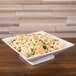 A CAC Citysquare bright white porcelain bowl filled with pasta and olives on a wood surface.