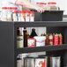 A woman using a black Cambro utility cart in a professional kitchen.