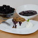 A plate of Lucky Leaf blackberry cobbler with a bowl of blackberries and a fork.