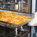 A person putting french fries in a Rational CombiFry tray.