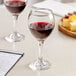 Two Acopa wine glasses filled with red wine on a table.