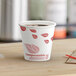 An EcoChoice paper hot cup of coffee with red leaf print on the counter.