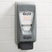 A GOJO® gray hand sanitizer dispenser on a tile wall.