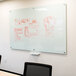 A white Aarco pure glass markerboard with red writing on it.