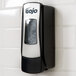 A GOJO® chrome ADX-7 soap dispenser on a tile wall.
