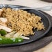 A Lodge oval cast iron fajita skillet with rice, chicken, and peppers on a table.