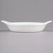 An oval white stoneware dish with handles.