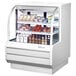 A Turbo Air white refrigerated deli case with food displayed inside.