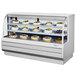 A white Turbo Air dry bakery display case with cakes and pastries on it.