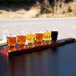 A mahogany flight paddle holding Libbey Mini Pub Tasting Glasses filled with beer on a table in a brewery tasting room.