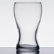 A close-up of a clear Libbey Mini Pub Beer Tasting Glass on a table.
