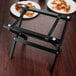 A black frame with Tablecraft Mini Table Tray Stand with plates of pizza on a table.