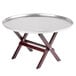 A silver Tablecraft mini table tray stand with mahogany legs on a table.