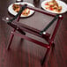 A Tablecraft mahogany mini table tray stand holding two plates of pizza.