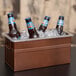 A copper and stainless steel rectangular beverage tub with a clear food pan containing bottles of beer on ice.