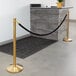 A Lancaster Table & Seating gold rope barrier in front of a reception desk.