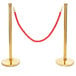 Two Lancaster Table & Seating gold metal poles with a red rope.