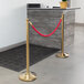 A gold rope tied to a Lancaster Table & Seating crowd control stanchion pole.