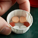 A hand holding a Genpak paper squat portion cup filled with pills.